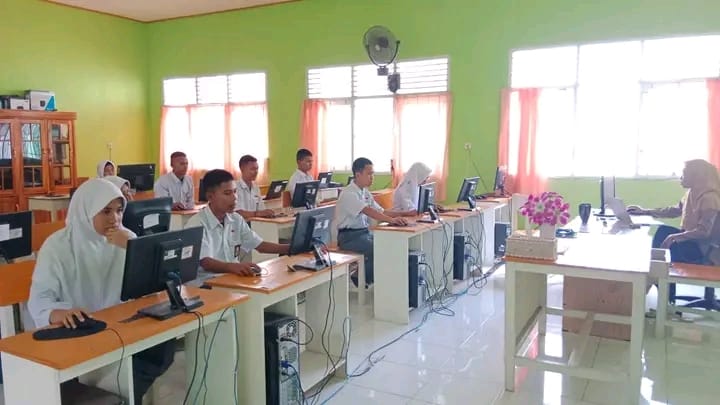 Anggota Komputer Club sedang berdiskusi di depan laptop